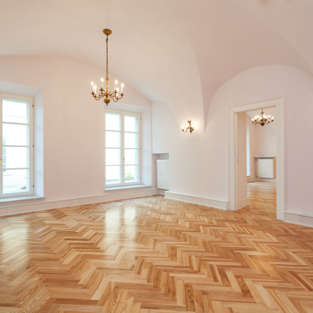 Interior of an empty palace with a wooden floor and chandelier.